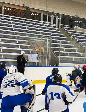 Coach instructing youth hockey players on the ice rink during practice.