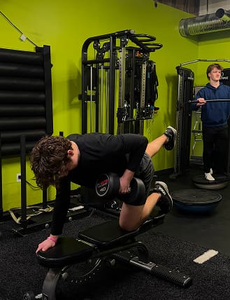 Man performing dumbbell row exercise in a gym.