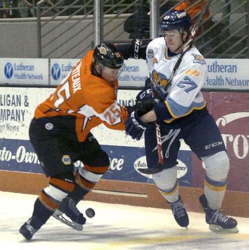Two ice hockey players competing intensely on the rink.