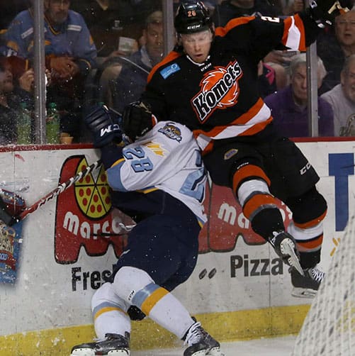 Hockey players collide near the rink boards during a game.